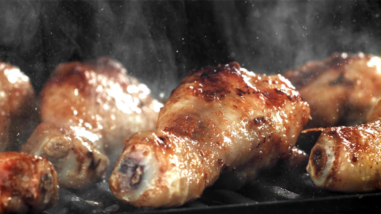 Fusi di pollo sfrigolanti in cottura su una griglia calda