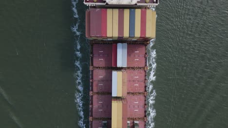 container ship loaded passing by, leaving trail of foam in water