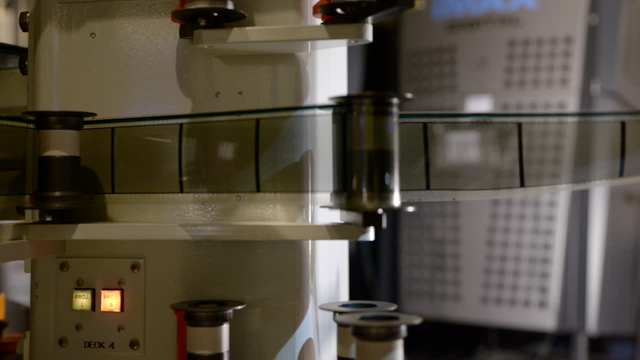 Medium shot of hands threading 70mm IMAX film through rollers