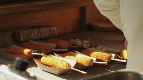 cooking corn dogs in boiling oil close-up. traditional asian corndog snacks street food. fried sausage in breadcrumbs on a stick. korean chinese street local market with traditional food. american fast food corndogs with sauce on the top. high quality 4k footage
