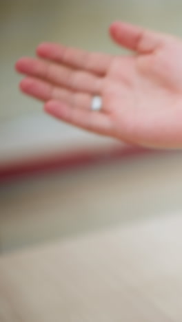 primer plano de la mano del hombre tatuado gesticulando en una conversación, con un fondo borroso que muestra el ambiente de la tienda minorista, la mano muestra un tatuaje y un anillo intrincados