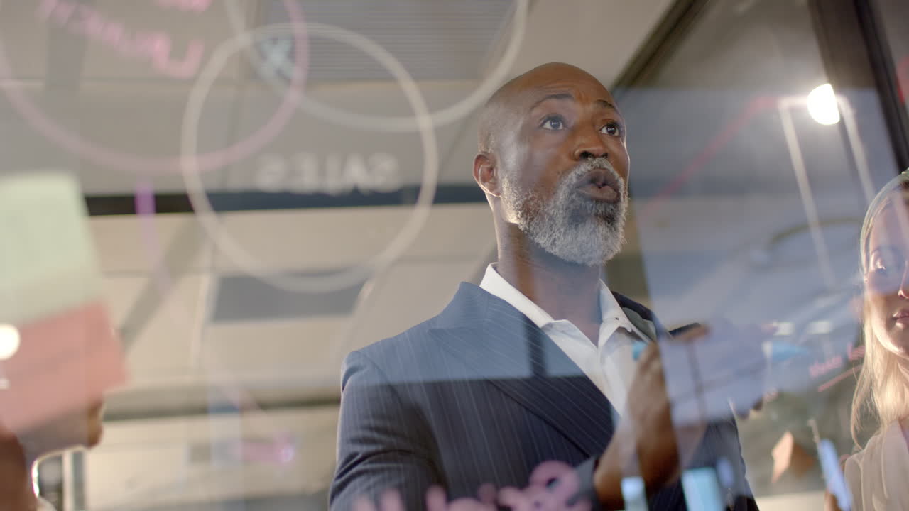 African american businessman writing on glass wall in office with copy space