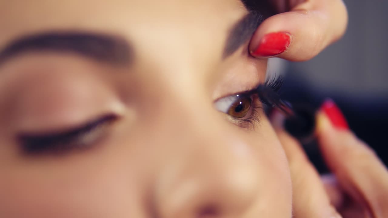 Close Up view of professional makeup artist applying mascara on the model's eyelashes. Work in beauty fashion industry. Backstage