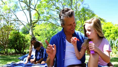 padre e hija soplando burbuja con varita de burbuja en un picnic en el parque 4k