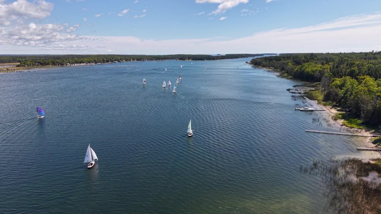 Vista aérea de drone de veleiros navegando em águas azuis calmas perto da costa de Hessel, Michigan