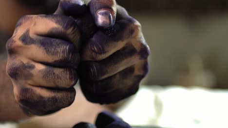 closeup shot of hands breaking dried madder dye balls during textile dyeing process