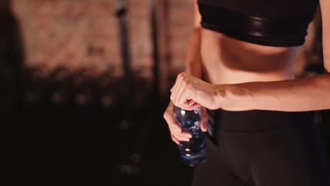 Midsection-Of-Young-Athletic-Woman-Holding-Water-Bottle-At-Fitness-Studio