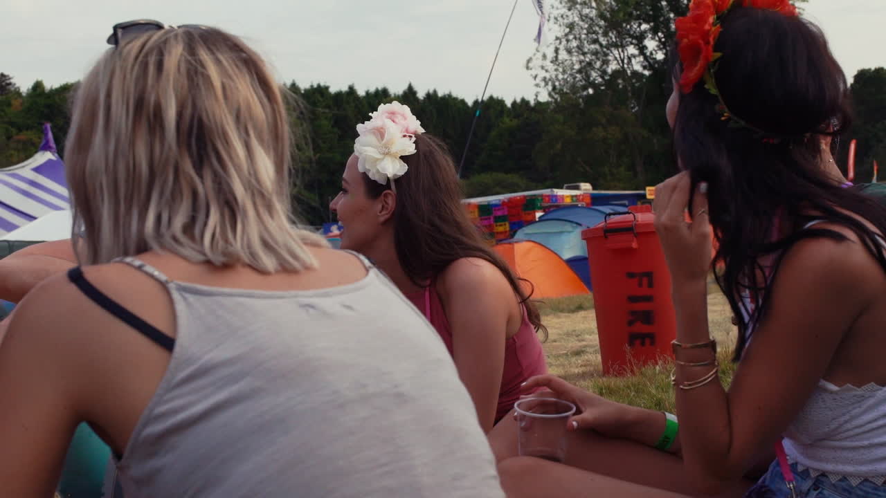 친구 들 이 음악 축제 캠핑장 에서 원 에 앉아 있다