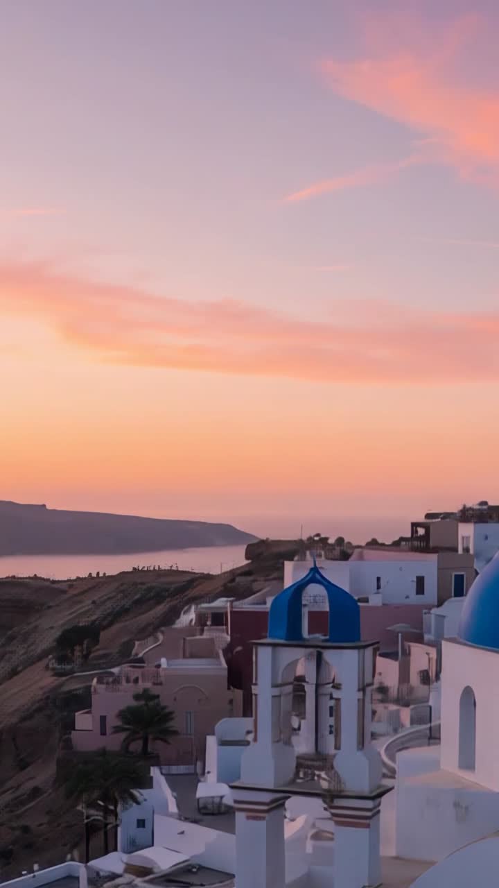 Vertical video: Sunset lighting blue-domed church bell tower in cliffside village over calm sea