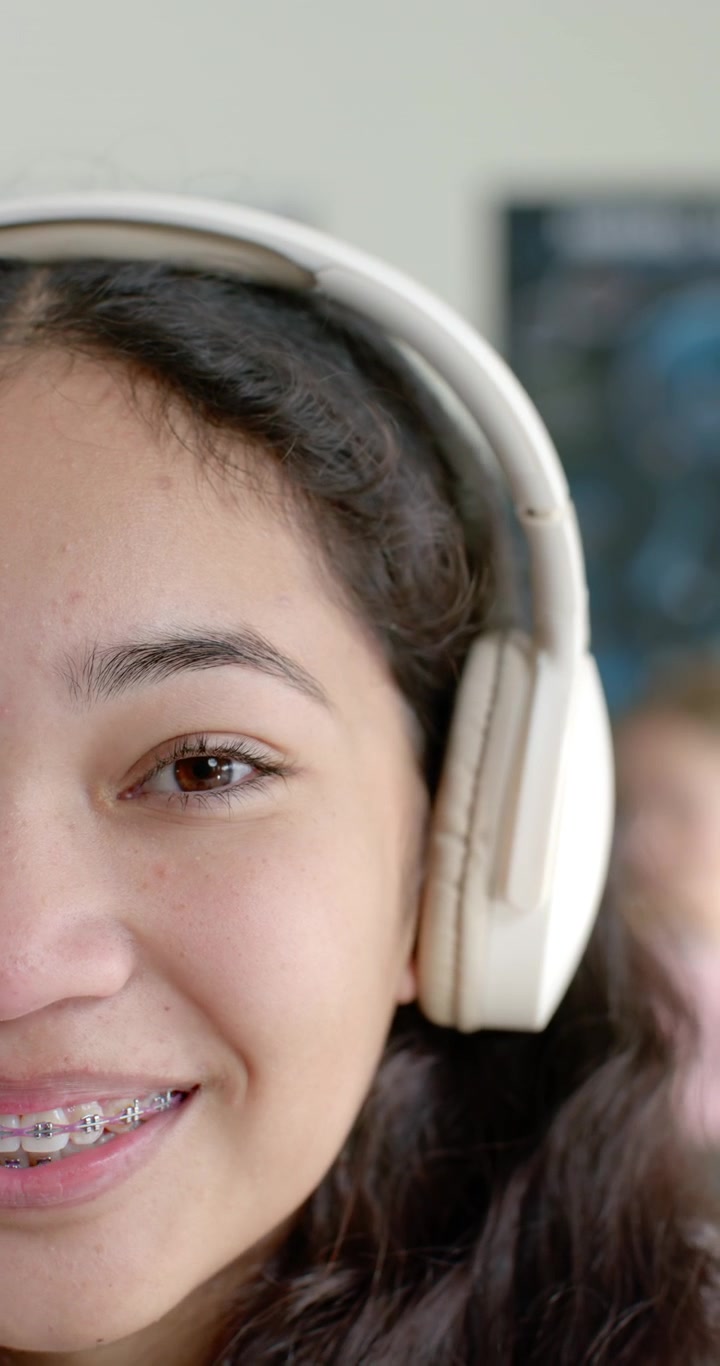 Vertical video: Song waking teen with headphones opening eyes and smiling showing braces in room