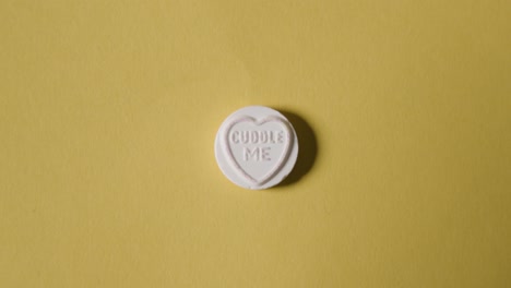 노란색 배경에 나를 안아주세요 메시지와 함께 심장 사탕을 손에 들고