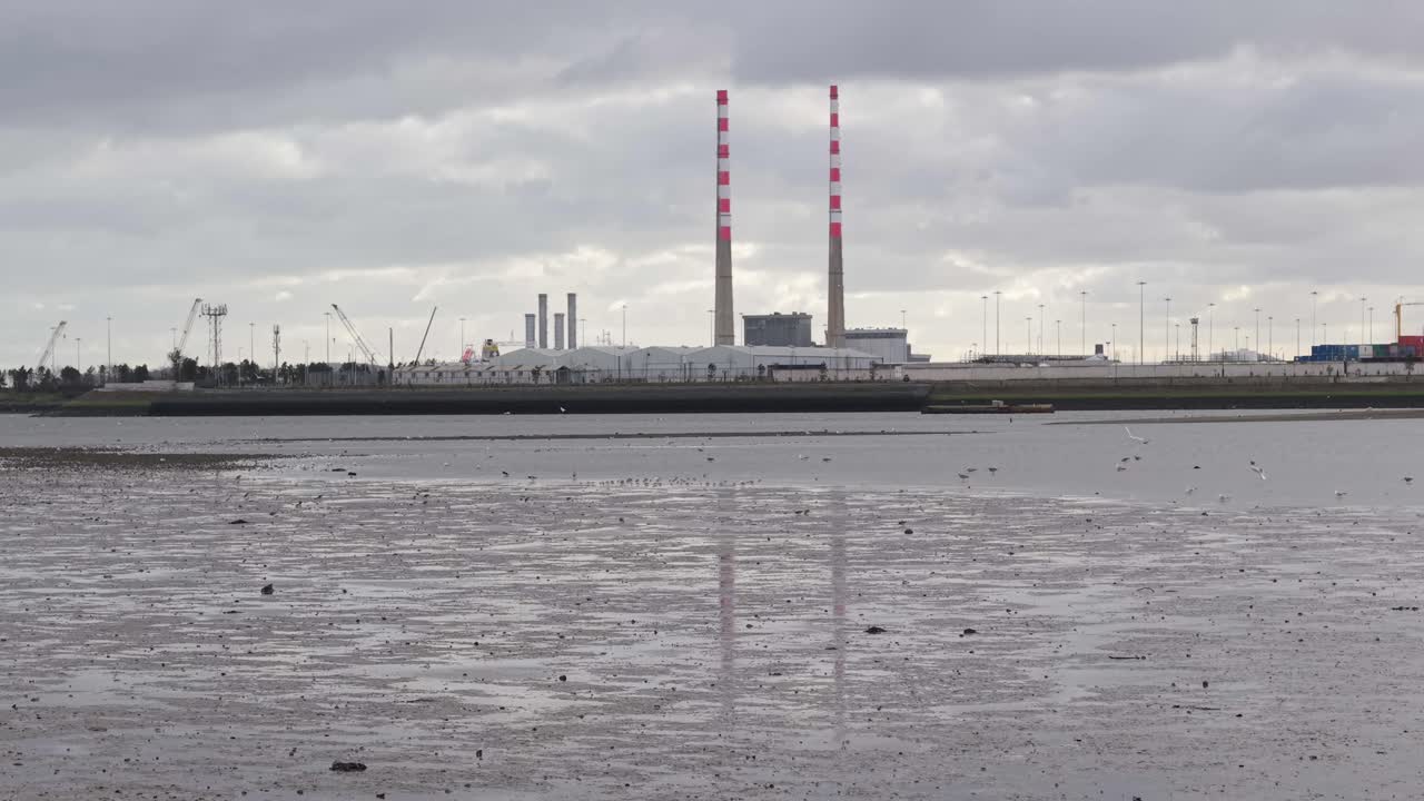 Industrial port with twin chimneys in Dublin, cloudy mood, calm low-tide waterfront