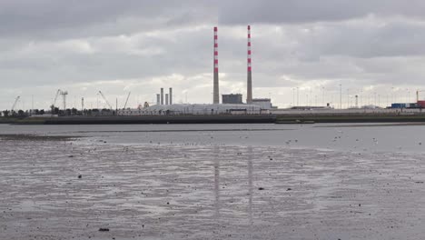 industrial port with twin chimneys in dublin, cloudy mood, calm low-tide waterfront