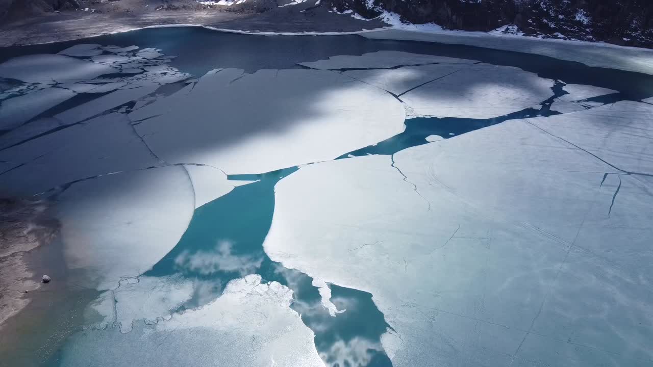 vista desde un dron sobre hielo flotante en un lago en los alpes, con el sol y las nubes reflejadas en el agua