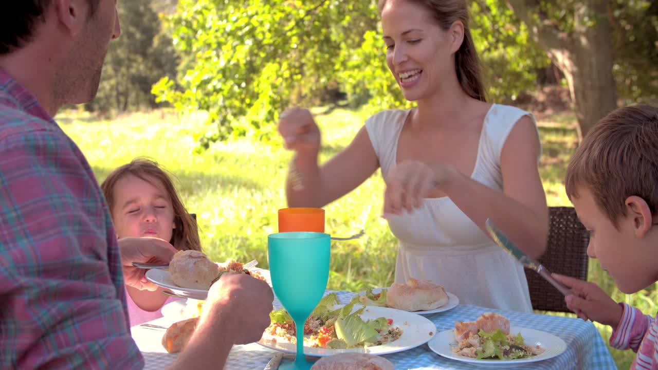 pareja con dos niños pequeños comiendo juntos al aire libre