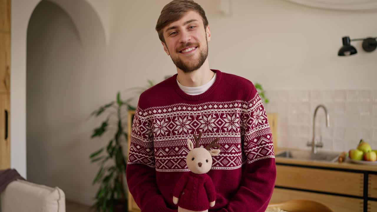 Smiling Man in Christmas Sweater with Reindeer Toy