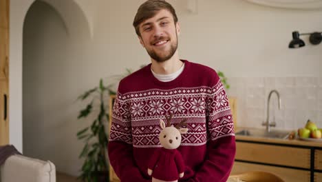 smiling man in christmas sweater with reindeer toy
