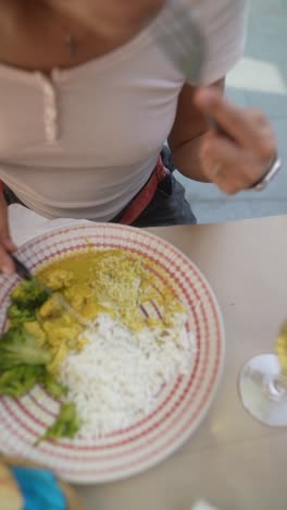 woman eating curry with rice and vegetables