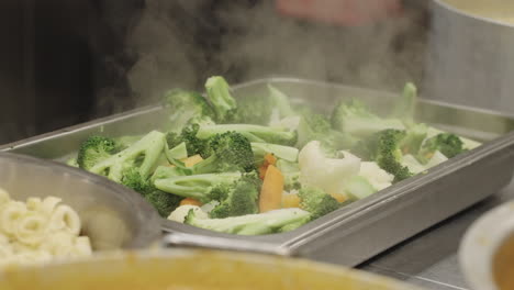 verduras calientes frescas y humeantes servidas en una sartén de acero inoxidable en la cocina de un restaurante