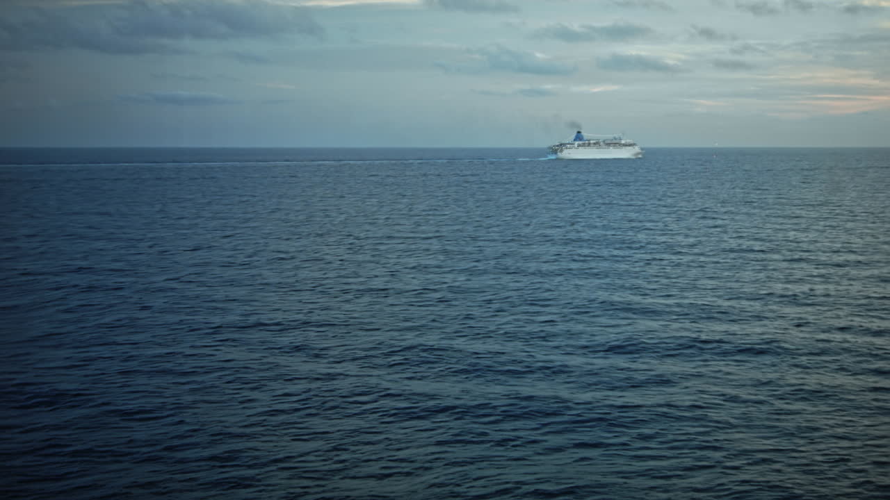 круизный лайнер в океане с небольшими волнами и вдалеке