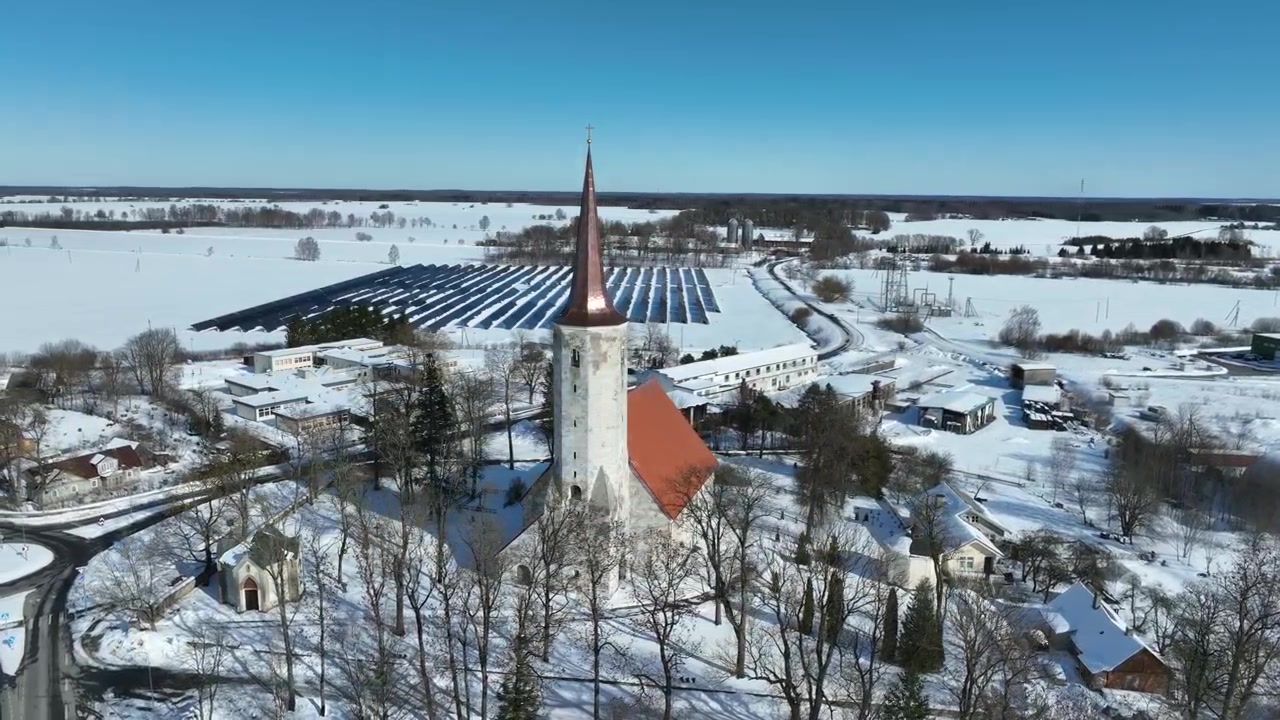 Vista aerea rotante della chiesa parrocchiale rurale di San Maurizio (St. Mauritius) a Haljala, centrale solare sullo sfondo. Estonia.