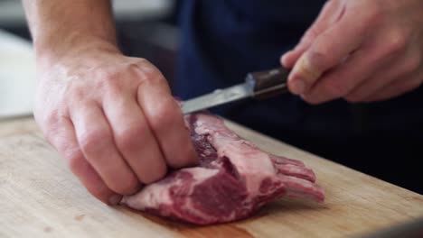 chef trimming fat of large rump of lamb