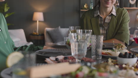 portrait of a happy woman talking with her family and laughing while sitting at dinner table at home