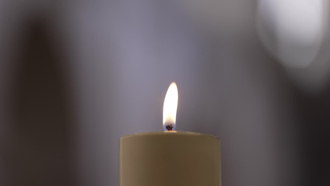 una singola fiamma di candela brucia dolcemente, offrendo un simbolo di speranza, pace e riflessione spirituale