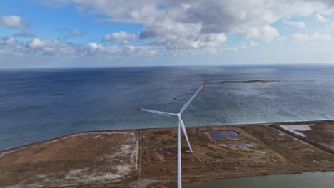 An-aerial-view-a-source-of-clean-energy,-four-wind-turbines-in-a-row-and-rotating-blades-on-a-summer-evening