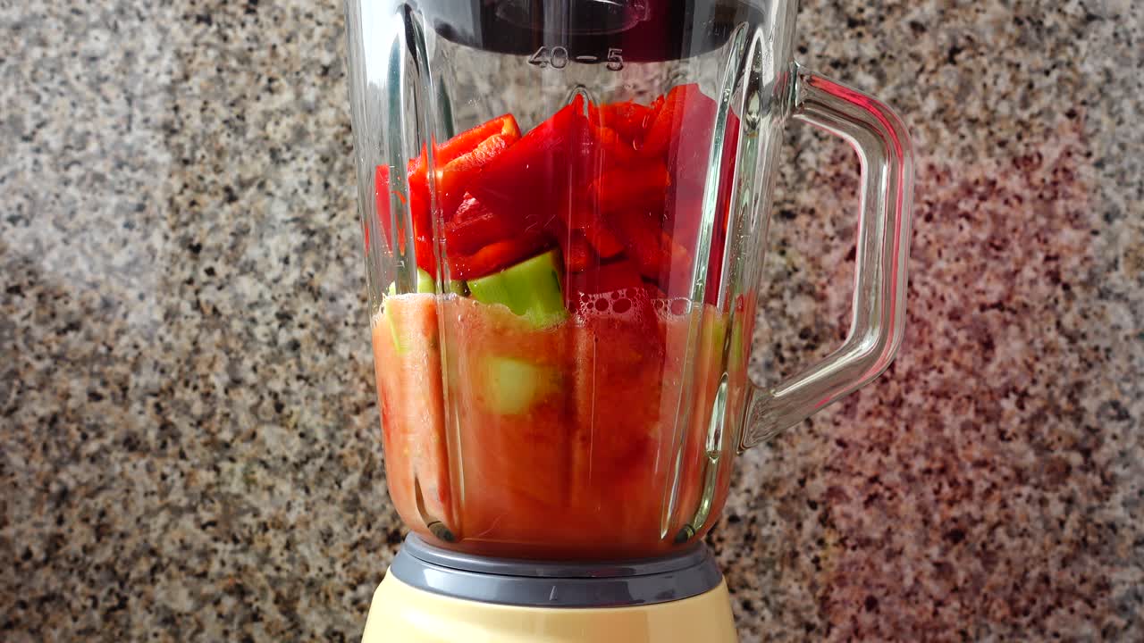 Riempimento del frullatore con pomodori, cetrioli e peperoni. Preparazione del Gazpacho nel frullatore.