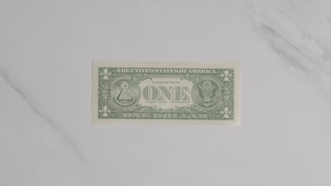 overhead currency shot of hand grabbing us 1 dollar bill on marble surface