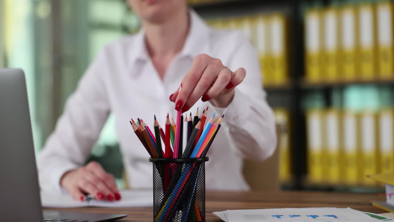 Woman selecting a colored pencil at her desk