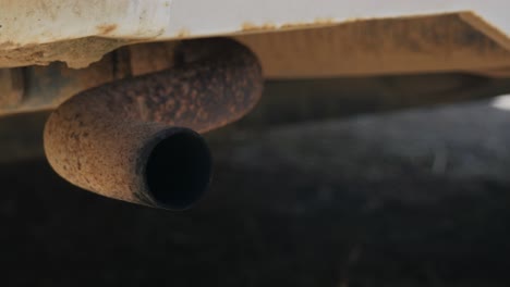 close up of an old vehicles tailpipe polluting the atmosphere with it's emissions