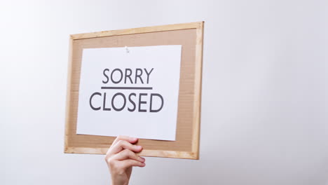 woman's hand shows the paper on board with the word sorry closed and flips to welcome open in white studio background with copy space