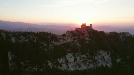 Three-towers-of-San-Marino,-Italy,-drone-move-up-view-during-sunset