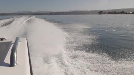 wake catches up speed boat as it slows while motoring in sunny lagoon