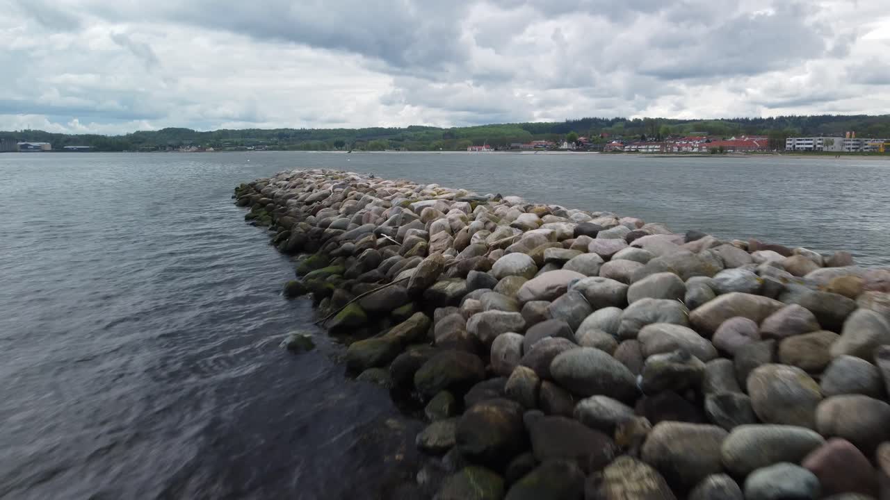 Drone shot of a stone jetty extending into the sea with a cloudy sky over Aabenraa