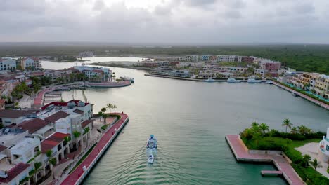 flying over a luxury white yacht tugging a dinghy through clear blue waterway in cap cana marina in dominican republic