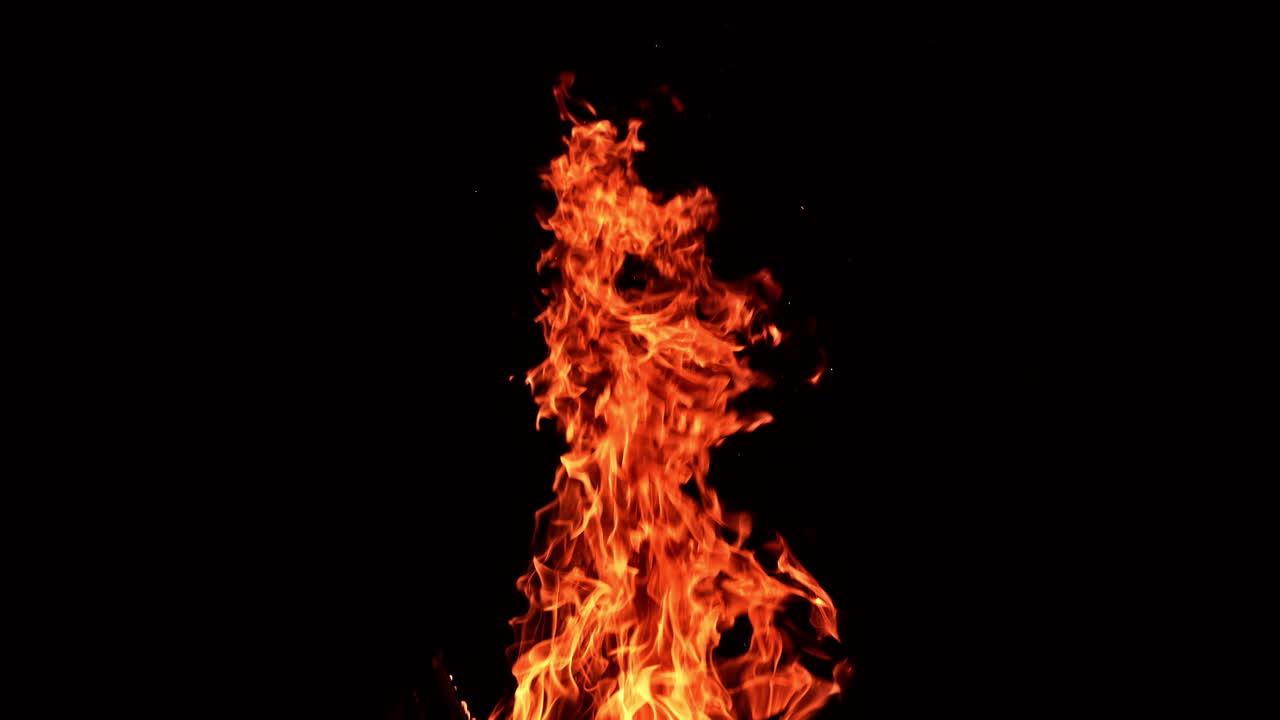 Huge burning fire with tiny sparkles flying up quickly. Flame of big bonfire striving up at black backdrop.