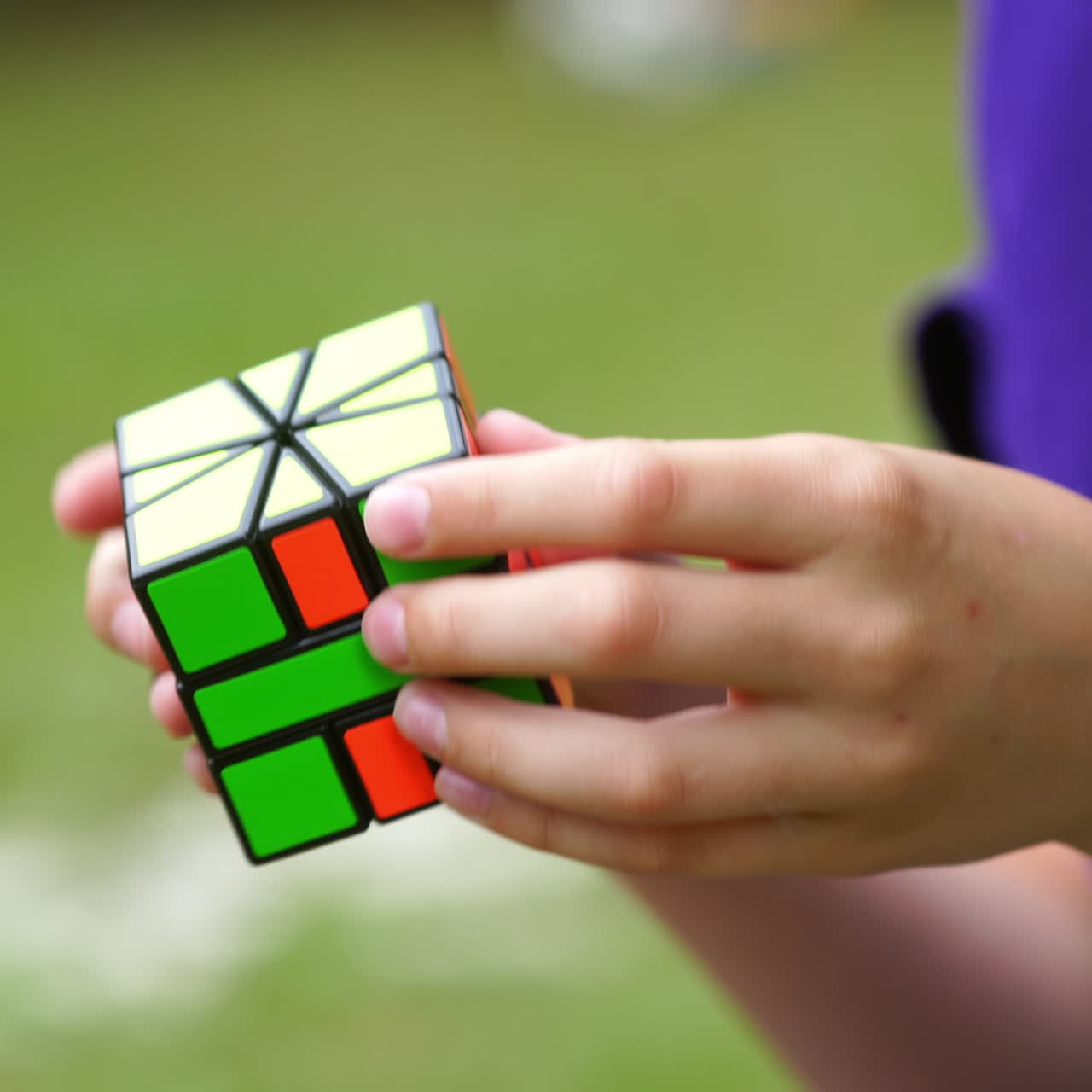 Rubik's cube in boy's hands on blurred background. Clever child brainstorms his mind while solving an intelligent game with cube. Concept of problem solving.