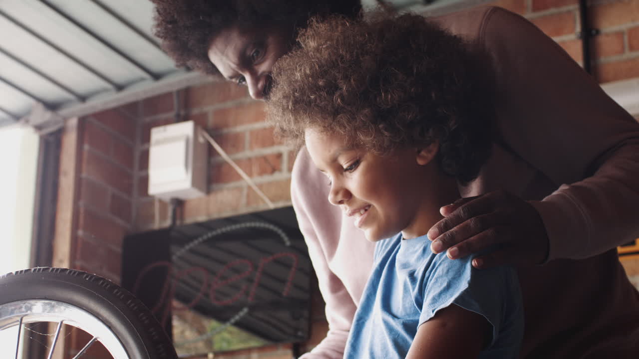 padre de mediana edad ayudando a su hijo pre-adolescente a usar una llave mientras hacen un kart de carreras juntos en el garaje, vista lateral