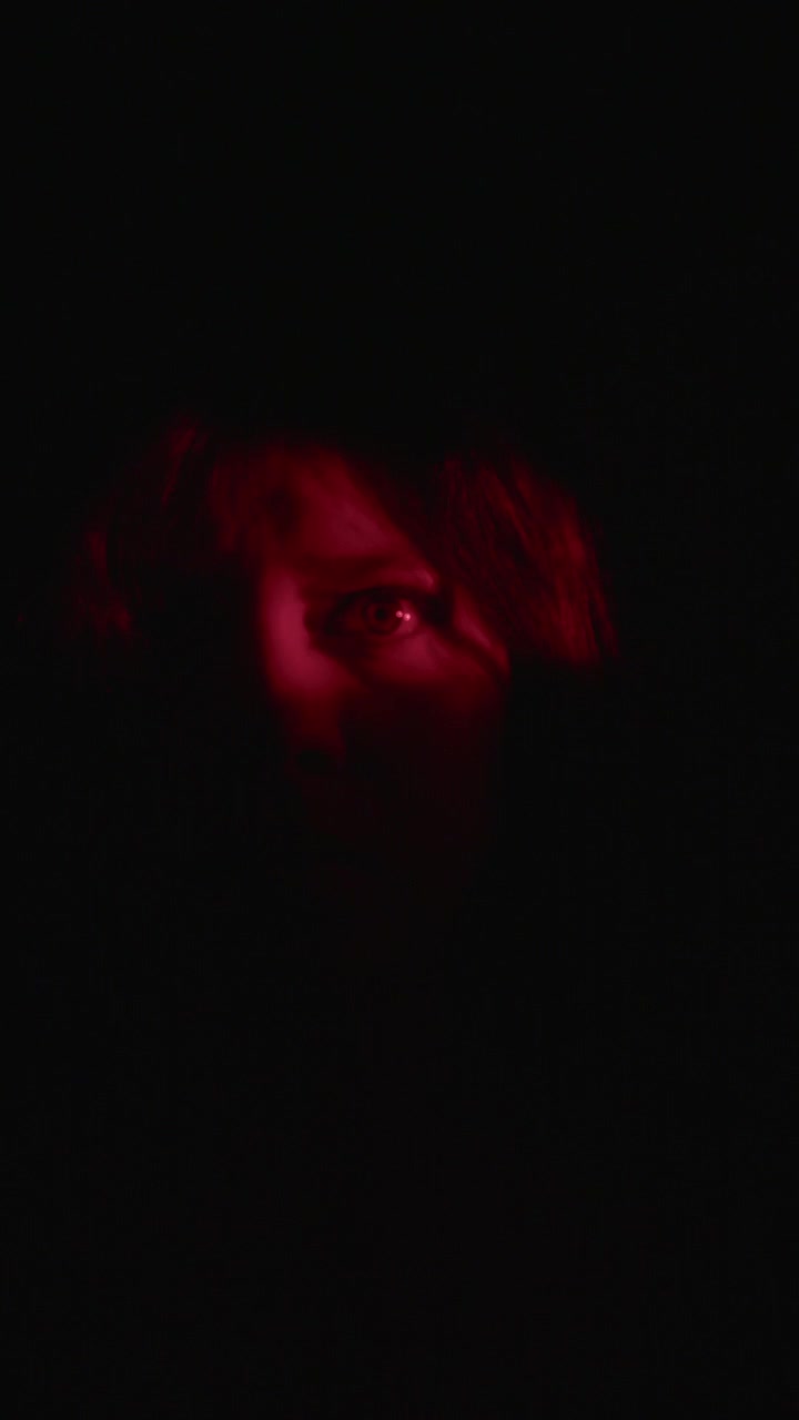 A dramatic vertical video featuring an enigmatic silhouette against a deep red light in darkness. The atmosphere is mysterious and intense, perfect for horror themes