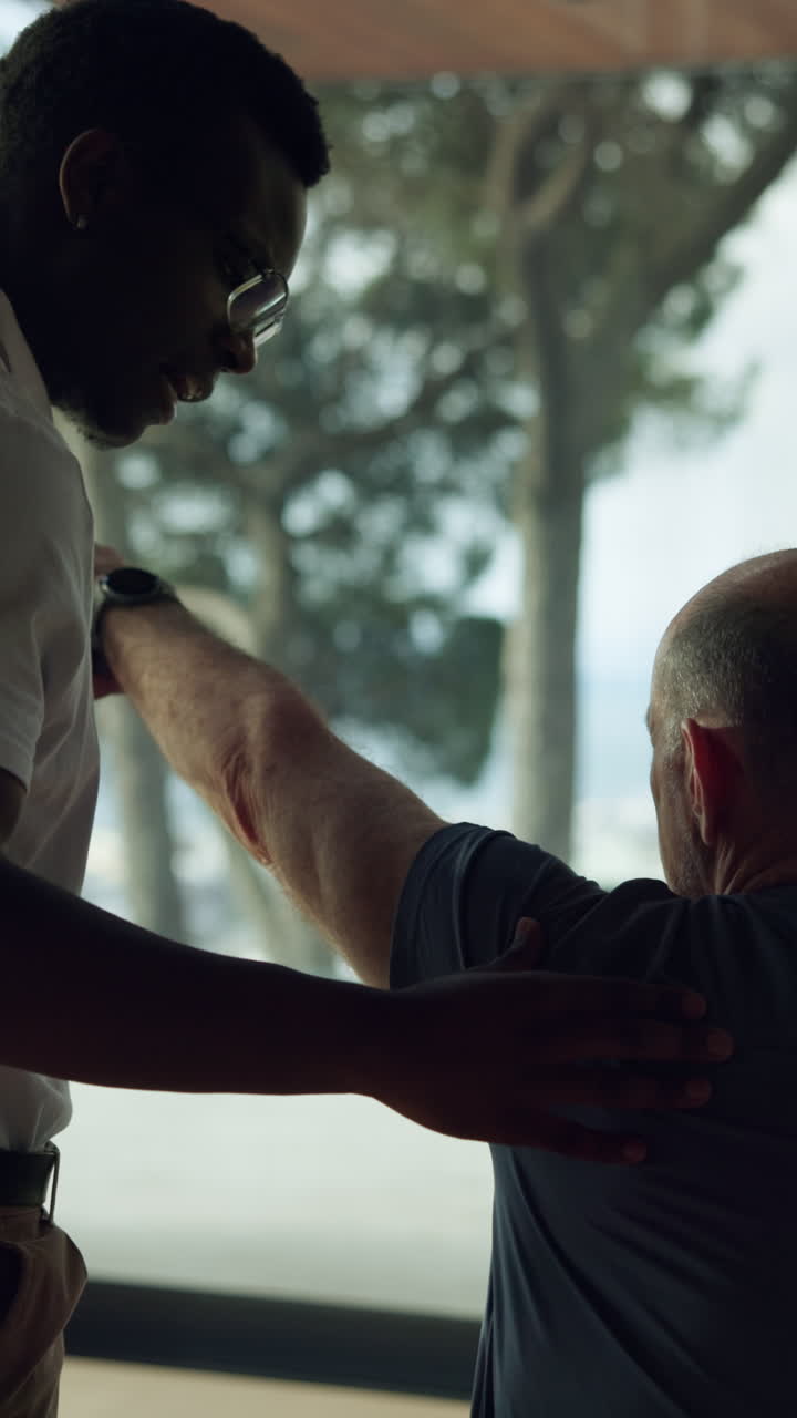 Young Therapist Assisting Senior Man with Arm Rehabilitation Exercise