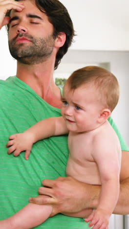 padre sosteniendo a su bebé y tiene dolor de cabeza