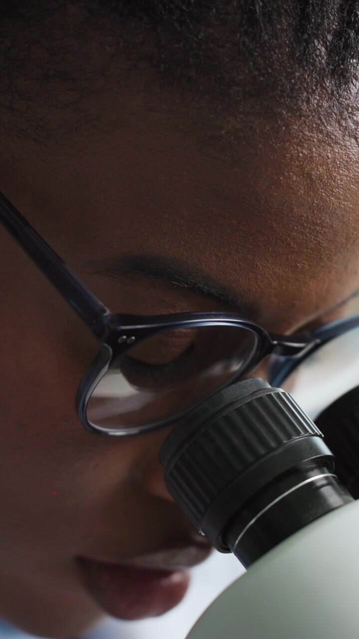Scientist Looking Through Microscope in Laboratory