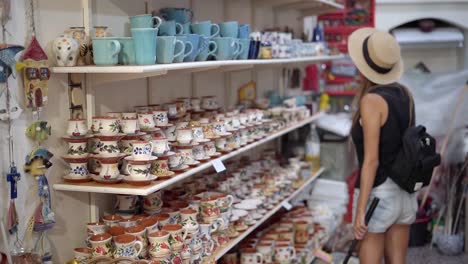 women tourist checking traditional handmade ceramic tea cups and coffee mugs at a shop in agiasos village, mytilene, lesvos, gimbal shot
