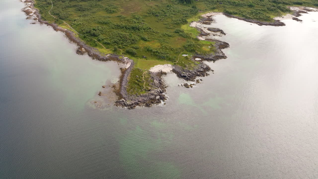 Rocky coastline and clear turquoise water, Årnessan, Stokmarknes, Norway. Aerial drone top-down orbiting