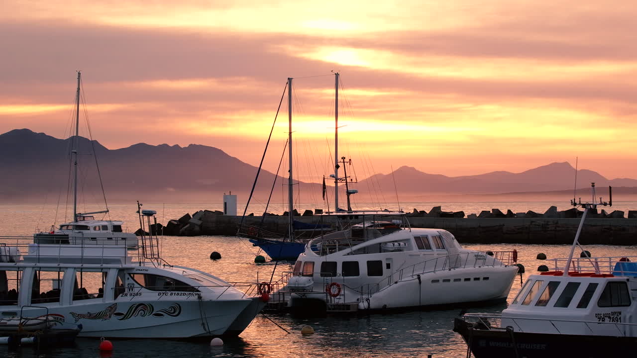 barcos de observación de ballenas que se mueven en el nuevo puerto, hermanus, amanecer cielo dorado