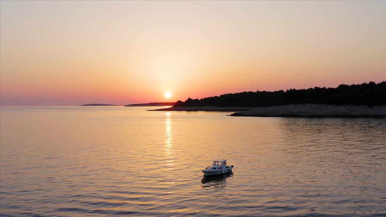 barco flotando en las tranquilas aguas del mar durante la puesta de sol púrpura en la bahía de losinj