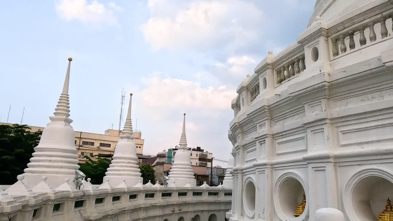 A serene view of Wat Prayurawongsawas temple's intricate white architecture under soft daylight in Bangkok, Thailand